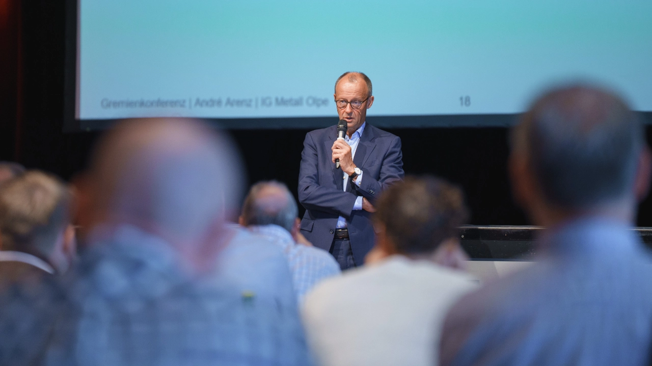 Friedrich Merz spricht vor Gremienkonferenz der IG Metall Olpe. Er spricht in ein Mikrofon vor den Teilnehmenden welche verschwommen im Vordergrund des Bildes sichtbar sind.