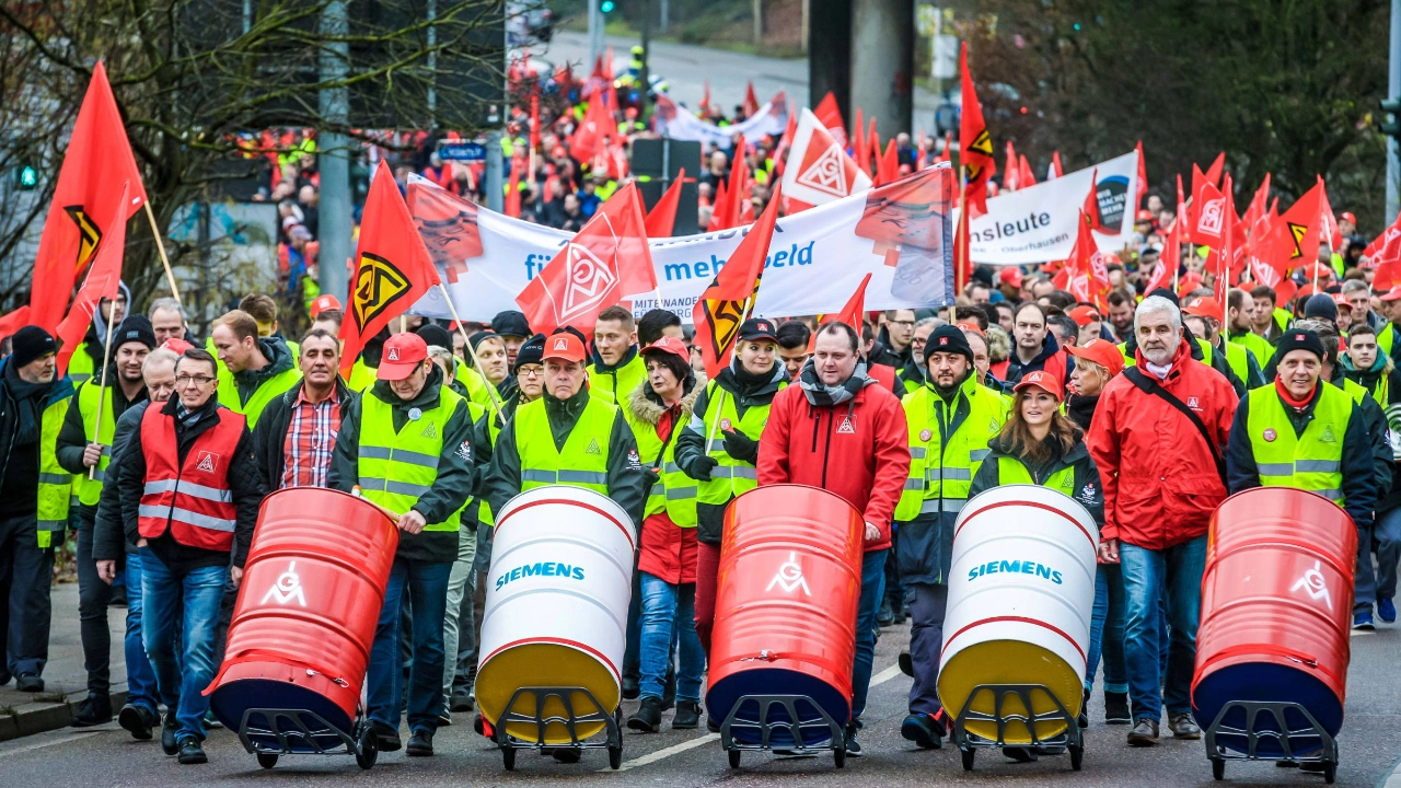 Streikende an der Spitze eines Demonstrationszuges, die auf Fässern trommeln.