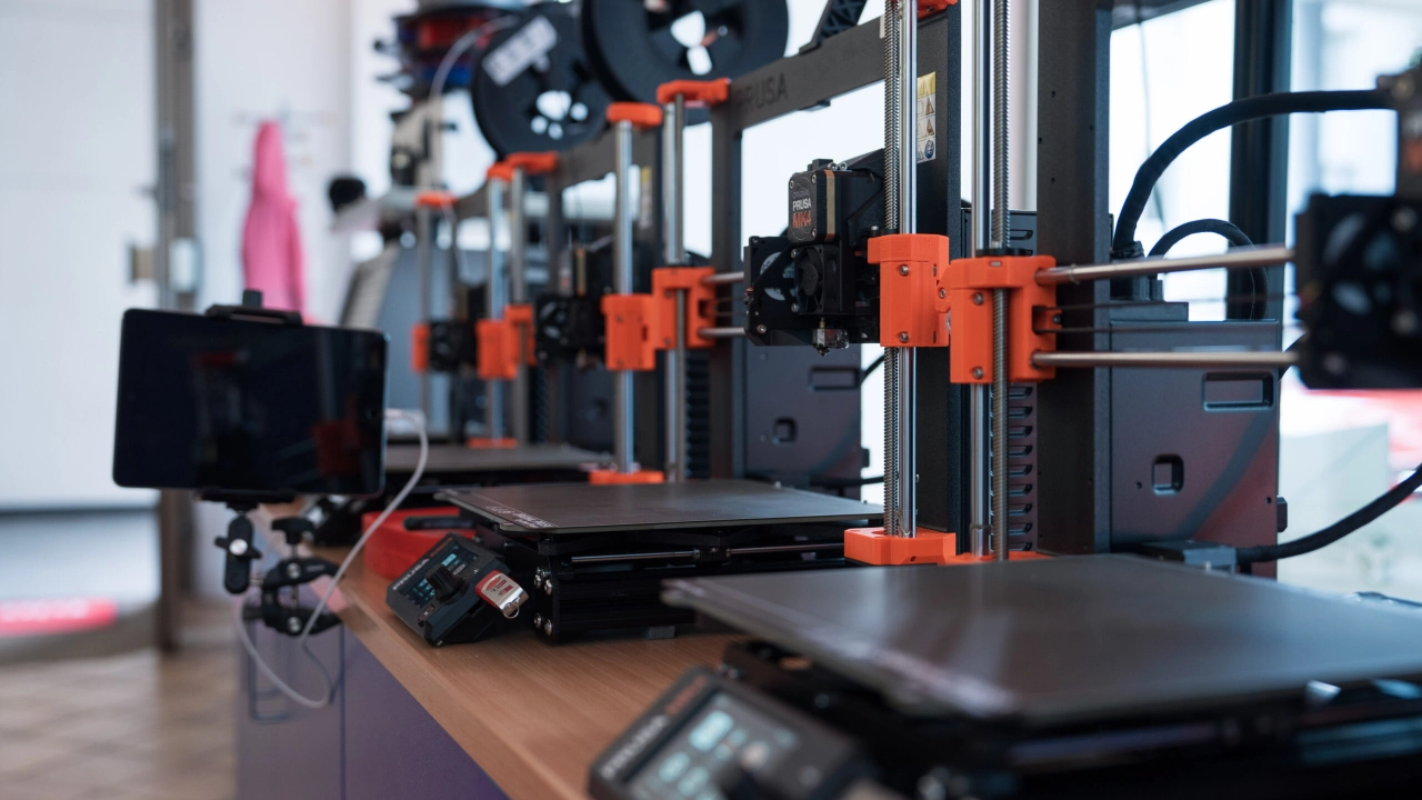 Eine Reihe von 3D Druckern die nebeneinander Stehen