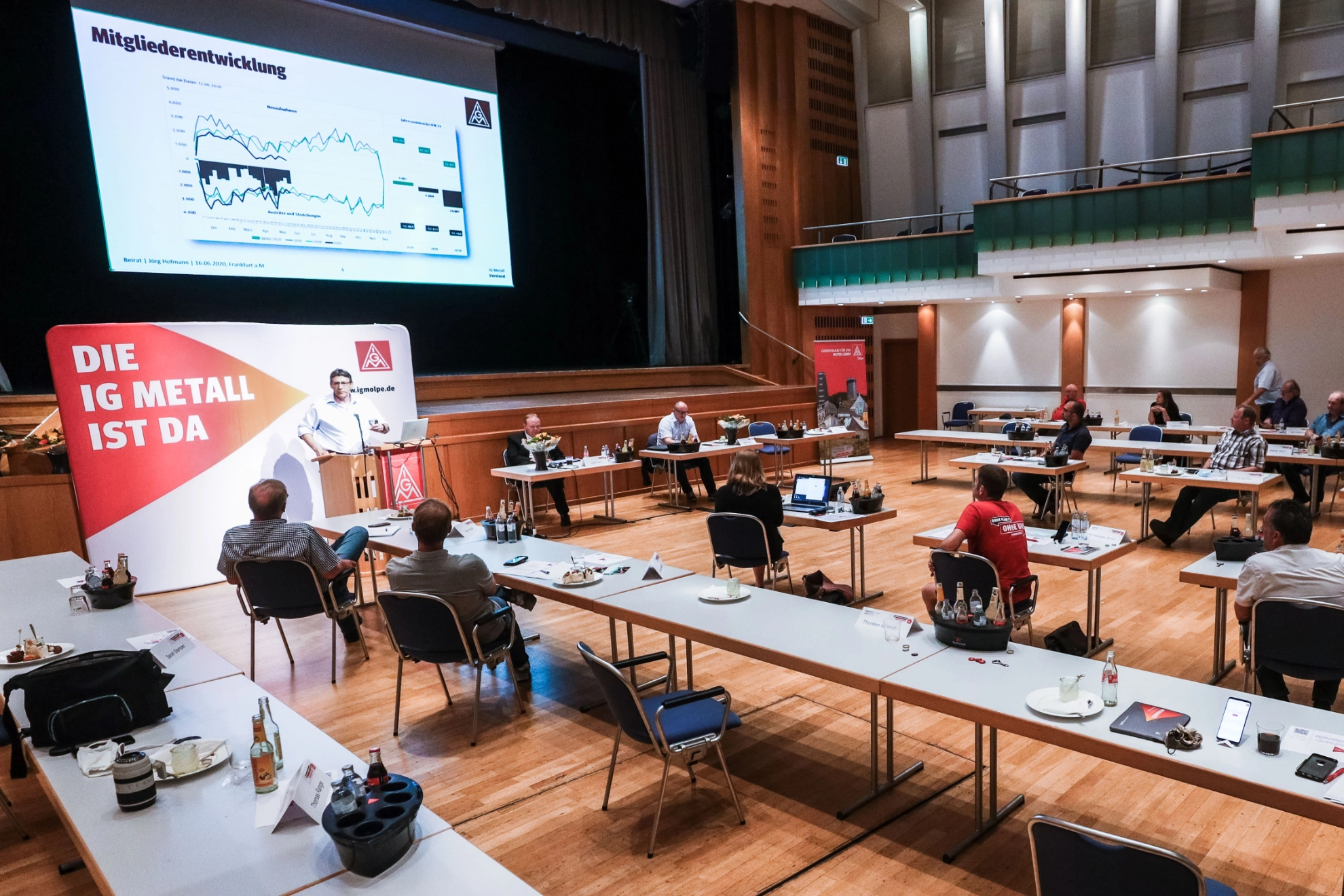 Teilnehmende sitzen mit viel Abstand in der Stadthalle Olpe und hören Knut Giesler zu. Es sind Kameras im Raum, welche die Veranstaltung als Video an Teilnehmende von Zuhause senden.