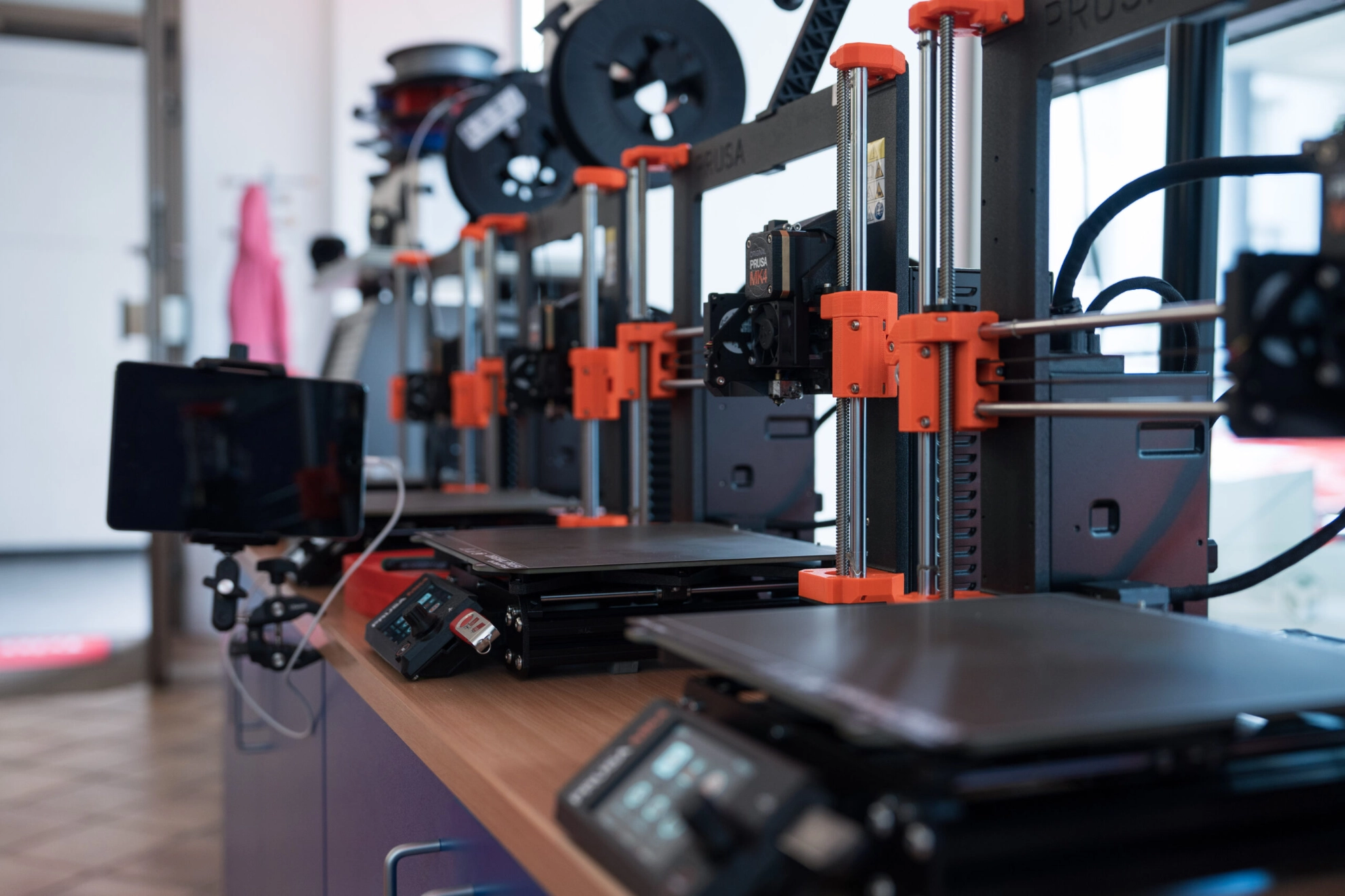 Eine Reihe von 3D Druckern die nebeneinander Stehen