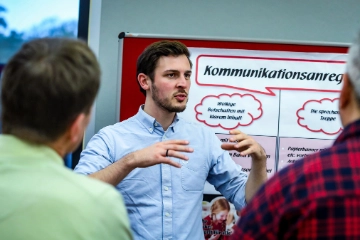 Junger Mann steht vor Flipchart und erklärt etwas.