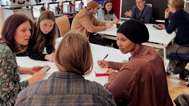 Eine Gruppe Teilnehmende spricht über Möglichkeiten und Projekte im Innovationslabor Olpe. Menschen sitzen an Gruppentischen und unterhalten sich.